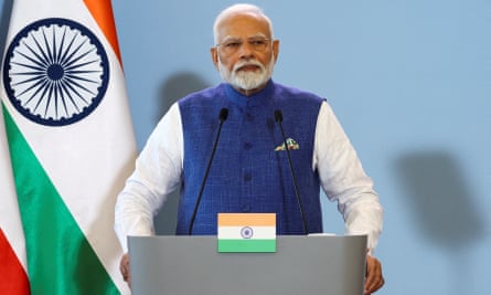 Narendra Modi standing at a podium in front India’s national flag