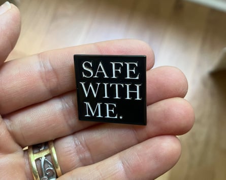 A hand holding a pin that says Safe with me