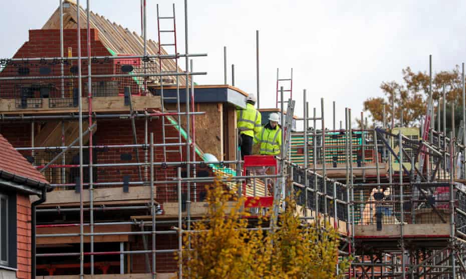 Construction workers on scaffolding around new houses being built