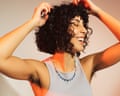 A woman with curly hair laughs joyfully, hands raised, showing unshaven underarms