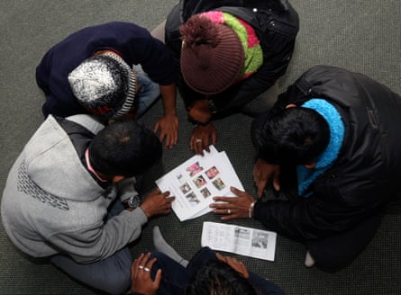 five children with their heads down looking at a paper