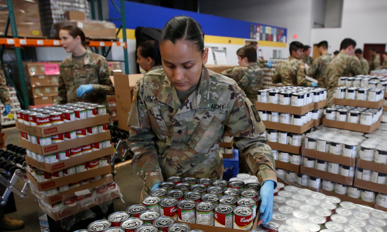Specialist Yadira Izaguirre of the California national guard picks up case of soup that will be packed with other supplies at a food bank in Sacramento, California.