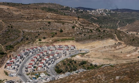 aerial view of rows of grey houses with red roofs in a hilly arid landscape
