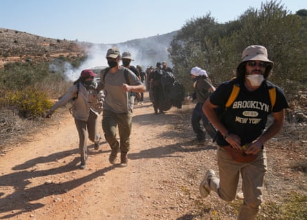 People wearing face masks running from a cloud of teargas