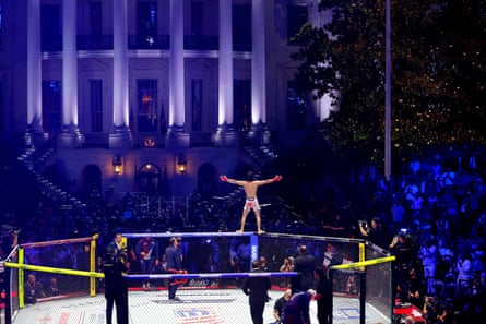 man stands on top edge of octagon ring and holds out arms in front of crowd