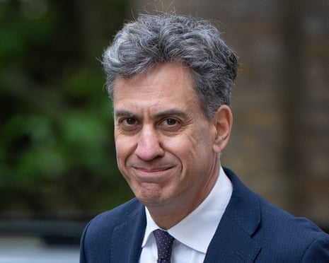 Ed Miliband in a navy suit and polka dot tie smiles at the camera outdoors.