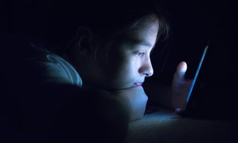 A teenager on a smartphone at night.