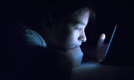 A teenager using a smartphone in bed
