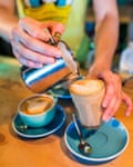 Person pouring a flat white into a glass cup