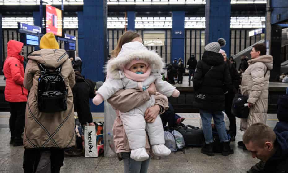 A mother holding her infant daughter on a train platform.