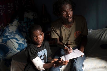Opposition activist Jean Charles Jean Clauzel, 41, with nine-year-old Dera Lourdjy in Solino, Port-au-Prince
