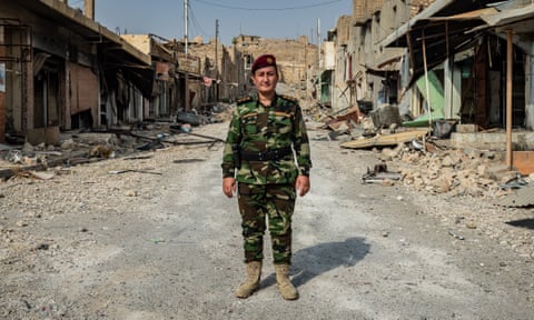 Khatoon Khider, in the uniform of her Peshmerga unit, stands amid the rubble of Sinjar market.