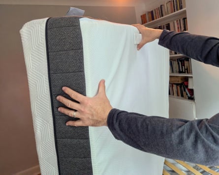 A man holds a Panda Hybrid Bamboo Mattress on its side
