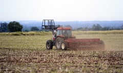 A farmer sowing barley in a dusty field in a tractor