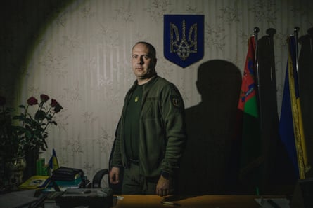 Serhiy Gorbunov posing at his desk in front of flags and a pendant