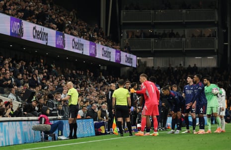 Referee Anthony Taylor looks at the VAR monitor before overturning Arsenal's penalty as the players look on.