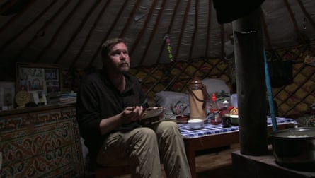 He eats dinner in a tent, looking lonely