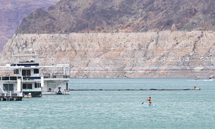 An image of a woman paddling in blue waters with a hill in the background