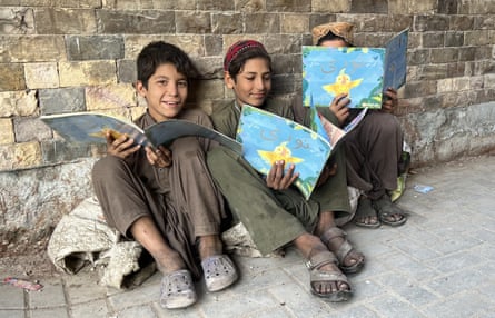 Three boys, smiling, each holding one of the storybooks