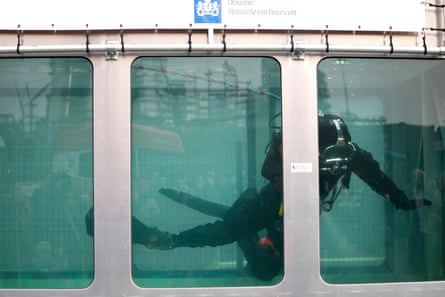 A scuba diver in a tank of water with Belgian customs/finance ministry insignia on it
