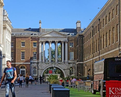 A stone archway sits between King's College buildings on a pedestrianised street