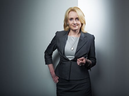 Julie Meyer wearing a dark-grey skirt and blazer and a pale-grey top, her left arm bent at the elbow and her hand held out in front of her, and her right hand on her hip