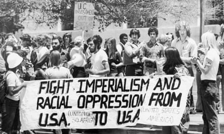 Black and white photo of group of students holding long banner (waist to sidewalk) that says Fight Imperialism and Racial Oppression from USA to USA,