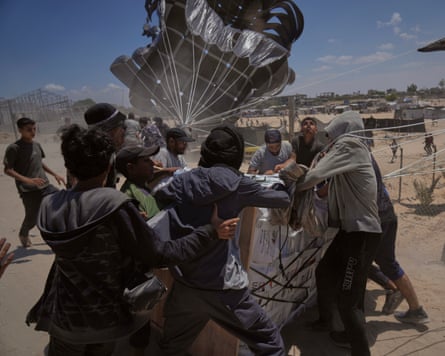 Palestinians rush to collect humanitarian aid airdropped by parachutes into Deir al-Balah, central Gaza Strip, 5 August.