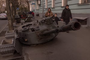 A family walks past a destroyed Russian armoured military vehicles on display in downtown Kyiv, Ukraine