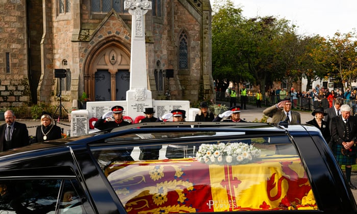 People salute as they stand in tribute as the cortege carrying the coffin of the late Queen Elizabeth II passes by in Ballater.