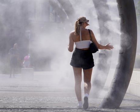 A lady cools off as she walks through a cooling water feature spraying a fine mist in Dover, Kent