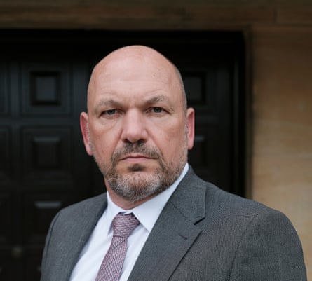 Jason Murphy looks directly at the camera and wears white shirt and grey tie and jacket