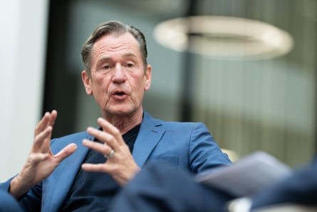 Mathias Döpfner speaking with his hands held up as he expresses himself. He is in his early 60s and has short greying hair in a side parting. He wears a blue jacket over a black top.
