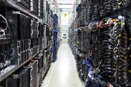 View down a row of black servers and multicoloured wires.