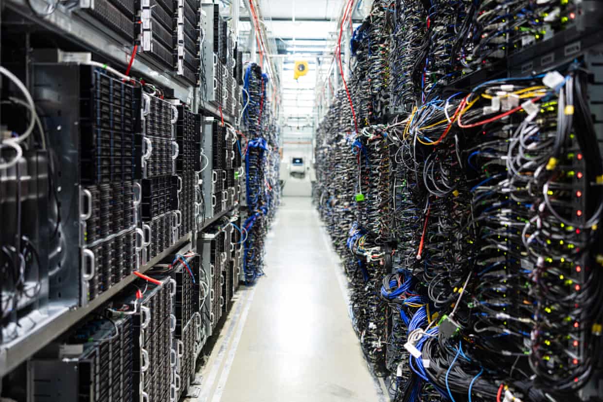 View down a row of black servers and multicoloured wires.
