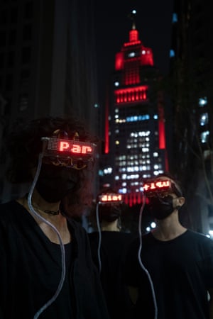 Two people with their eyes hidden by headsets walk through Buenos Aires at night