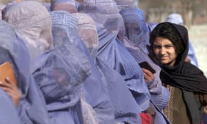 A girl waits to receive food aid among burka-wearing Afghan women during the UN food distribution scheme in Kabul, 13 December 2001.