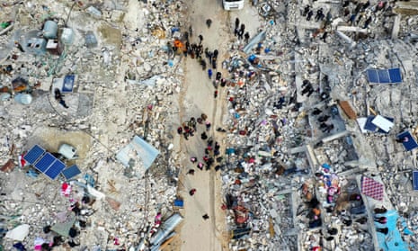 Residents search for victims and survivors amid the rubble of collapsed buildings in the village of Besnia.