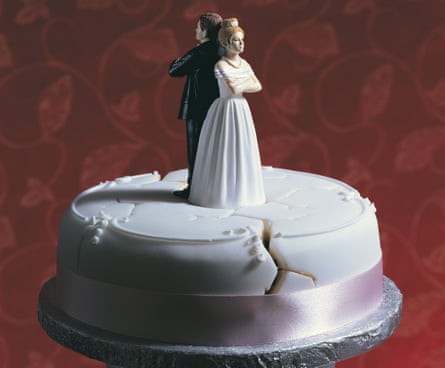 A damaged wedding cake, with bride and groom figures standing back to back