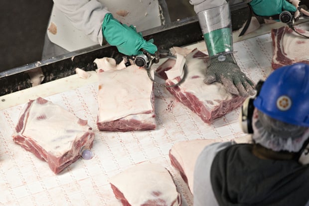 Employees trim fat from sections of pork at a US plant