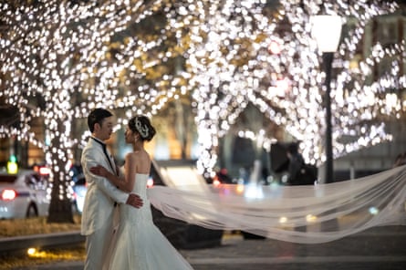 Wedding photo of a couple in wedding gear in Japan at night with fairy lights and a long veil