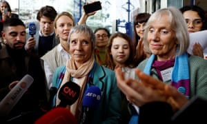 Two women speaking into microphones surrounded by supporters