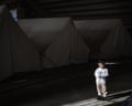 A displaced boy stands outside his family's tent at a temporary displacement camp in the Beirut Stadium on March 28, 2026 in Beirut, Lebanon. 