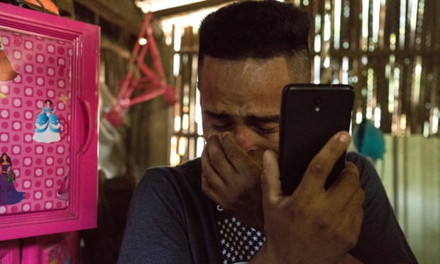 Arnovis de los Santos breaks down as he talks to his daughter on the phone inside his home in El Salvador.