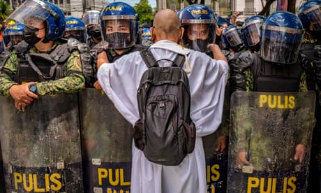 A Catholic priest talks to police officers as Filipinos  protest against election results outside the Commission on Elections building on Tuesday.