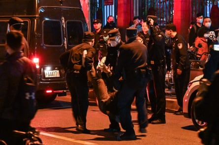 A man is arrested while people gather on a street in Shanghai on 27 November 2022.