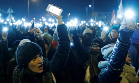 People hold up their mobile phones attend a protest against the proposed new labor law.