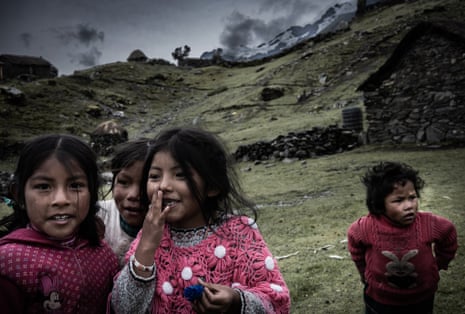 Children from the Queros community play beneath their homes in a hilly landscape