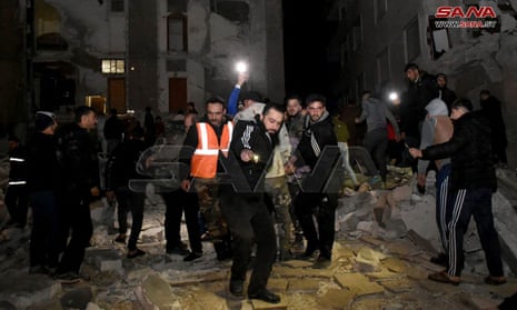 Rescuers evacuate a victim from an eight-storey building that collapsed in Hama, Syria