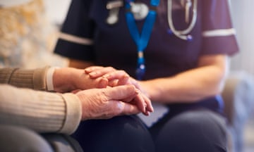 A nurse holding an elderly person's hands